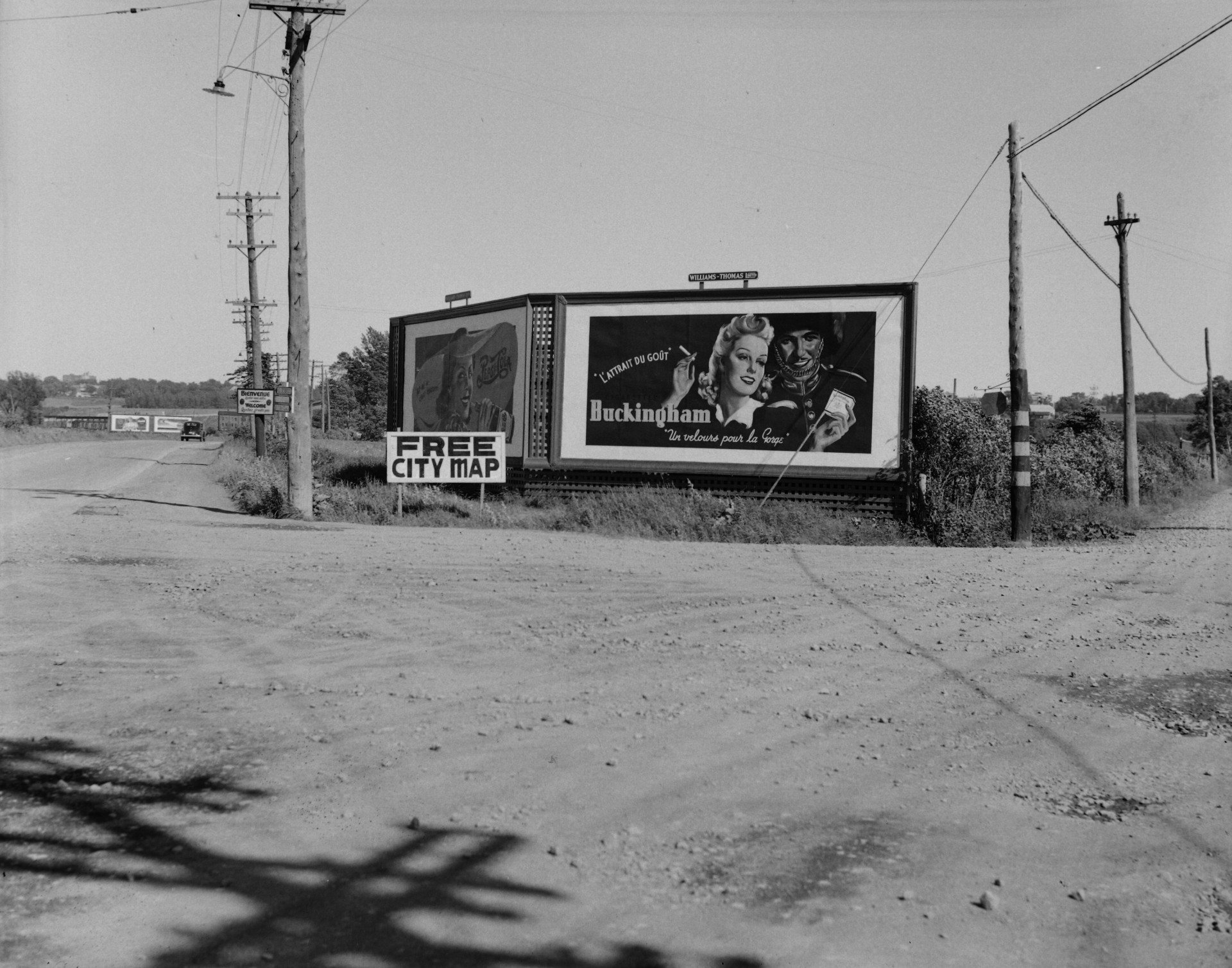 Il s'agit d'un négatif représentant des panneaux publicitaires situés à l'entrée de Québec. L'une d'entre elles annonce les cigarettes Buckingham. On y voit également une affiche sur laquelle on peut y lire : " Free City Map ".
