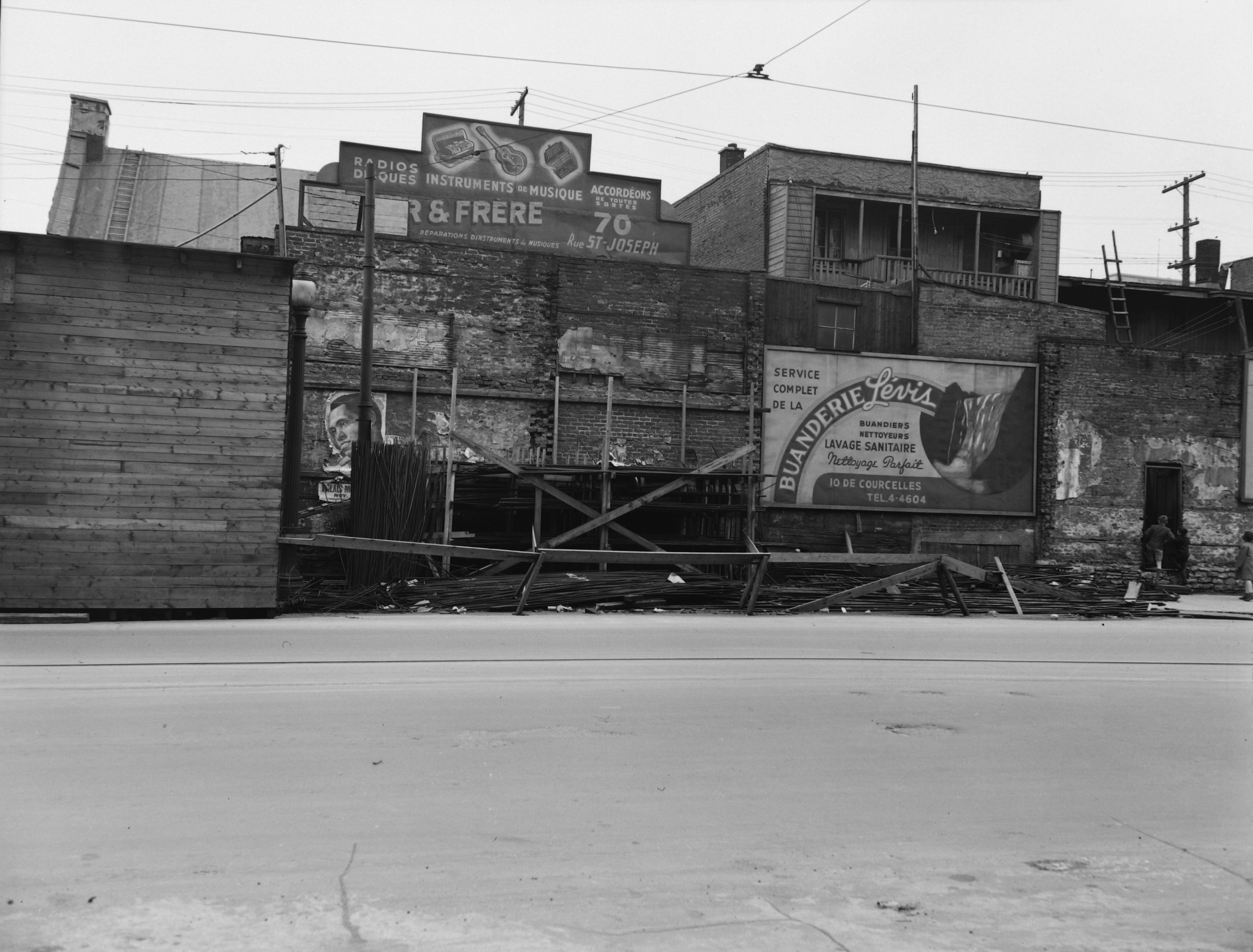 Il s'agit d'un négatif représentant des affiches publicitaires de Buanderie Lévis et d'un magasin de musique sur le boulevard Charest dans le quartier St-Roch.