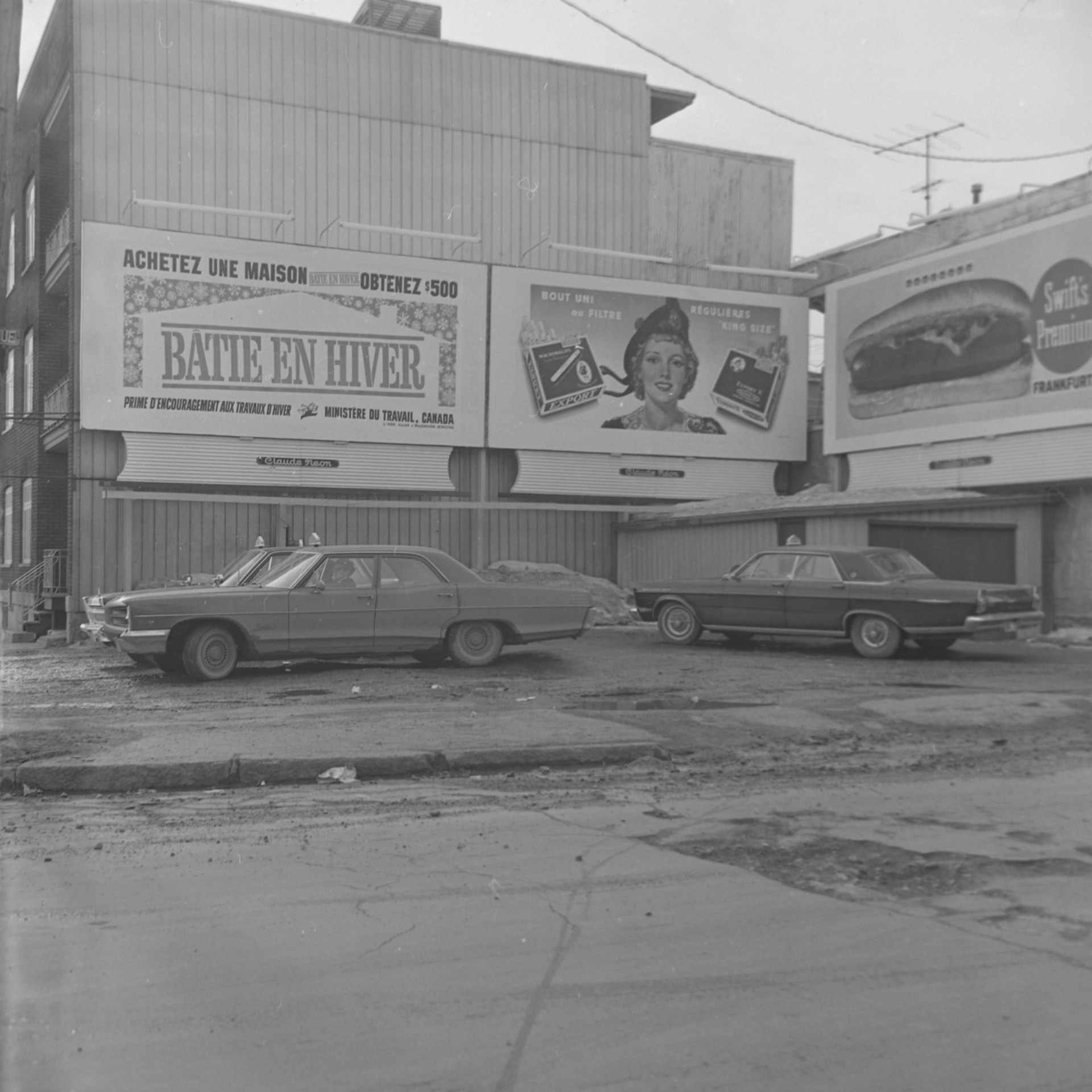 Il s'agit d'un négatif représentant des affiches publicitaires. On y voit des taxis qui sont stationnée.